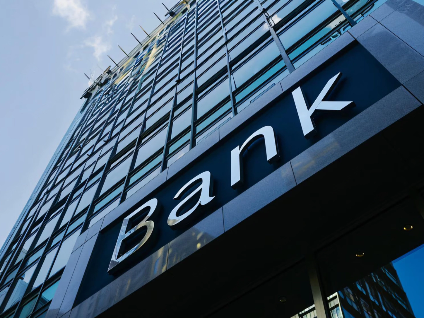 La scritta «Bank» sulla facciata di un grattacielo con vetrate, vista dal basso