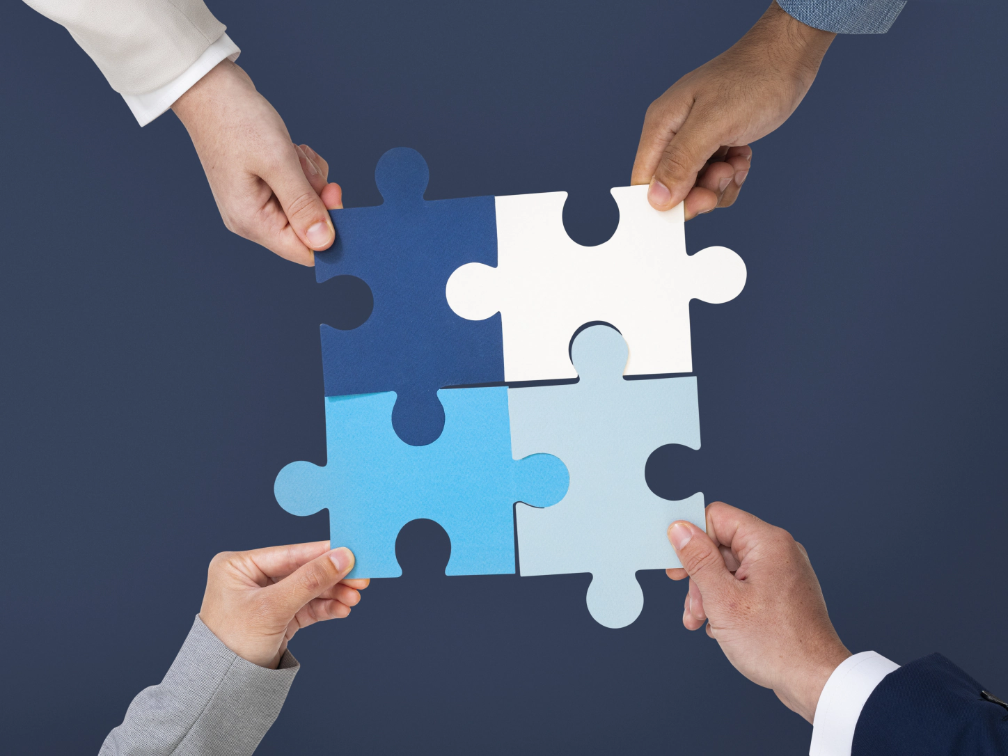 Quattro mani che uniscono i pezzi di un puzzle blu