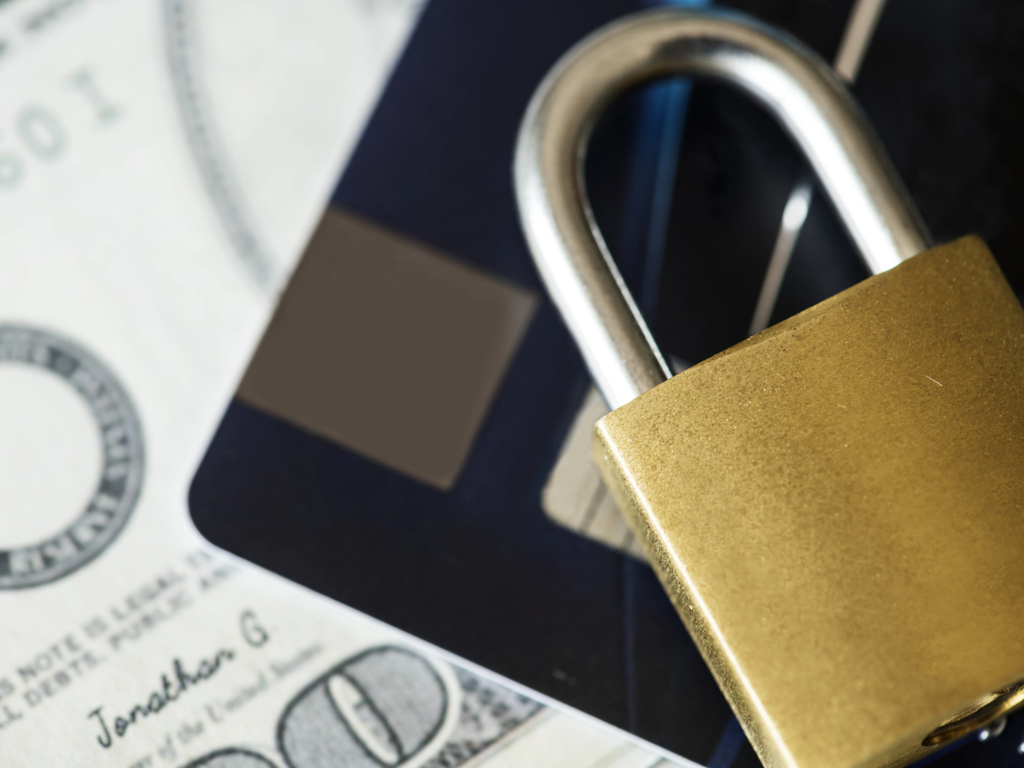 Un lucchetto dorato appoggiato su una carta di pagamento e una banconota
